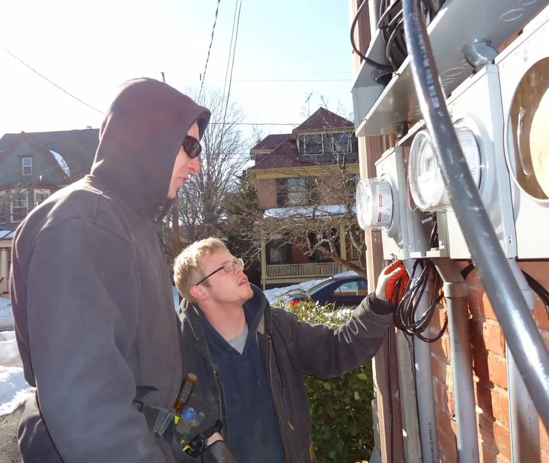 Electricians inspecting the electrical panels and meters on a multifamily house