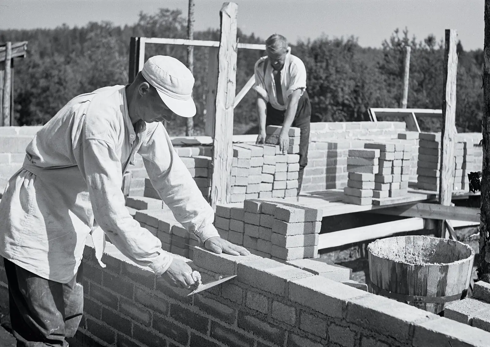 Bricklayers laying a brick wall, in a historic black-and-white photo