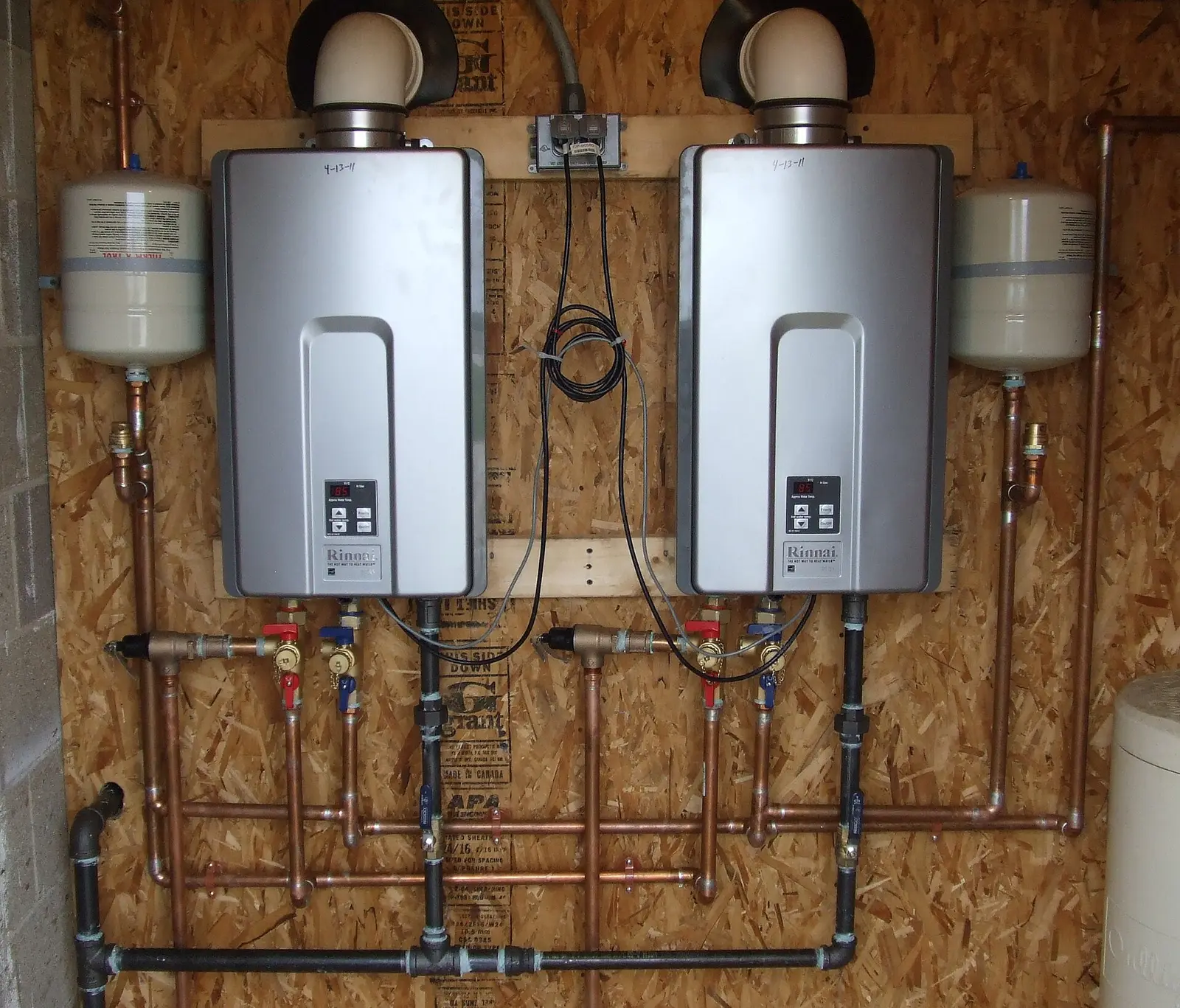 Two wall-mounted tankless water heaters plumbed with copper supply lines