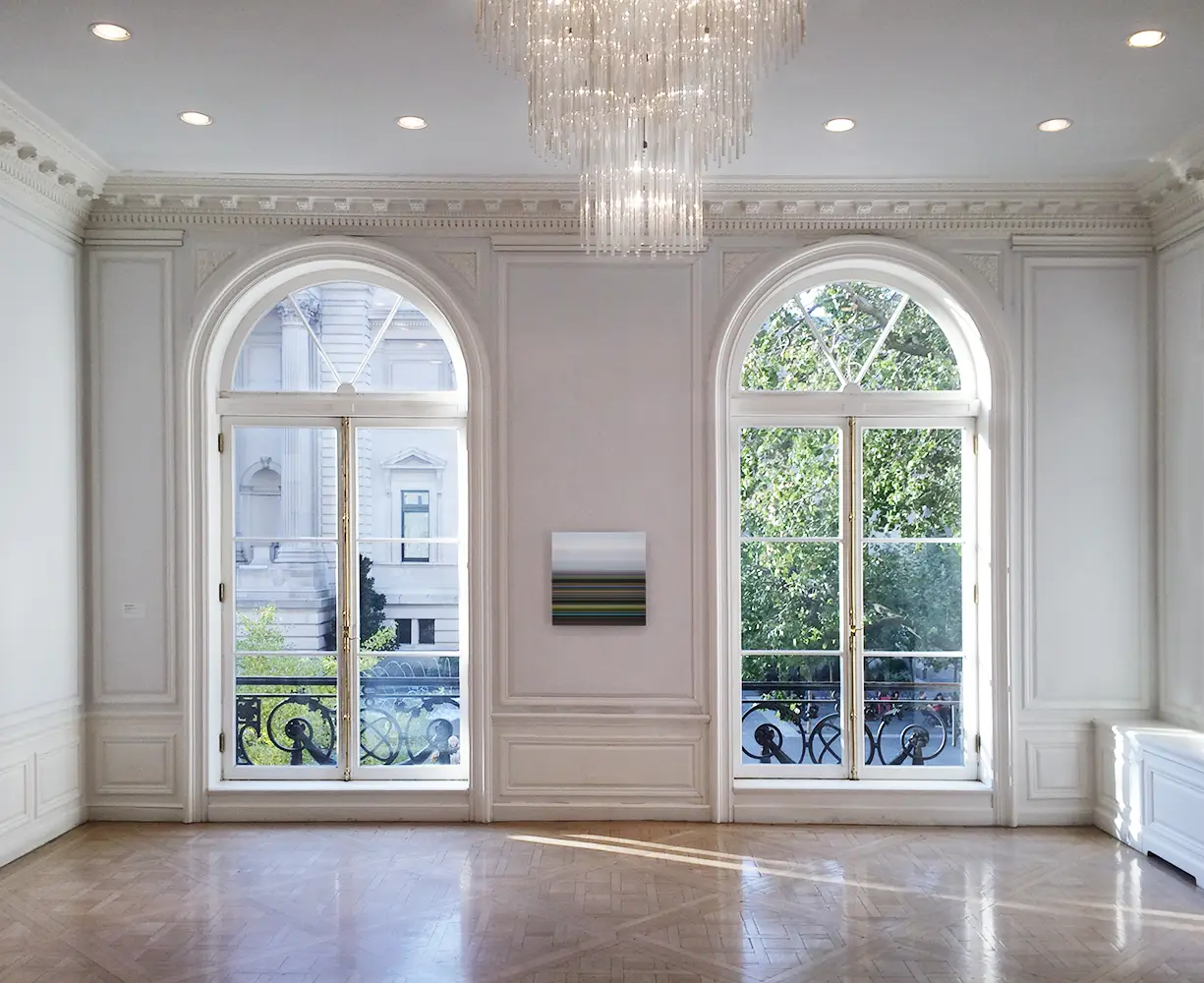 Tall arched double windows with divided panes in a white paneled room