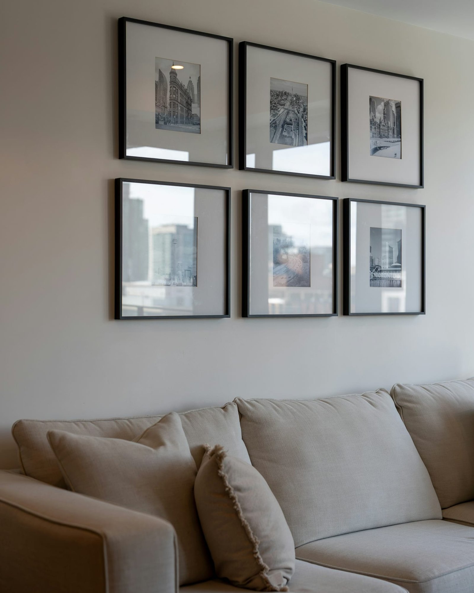 Six black-framed photographs hung in a neat grid above a beige sofa