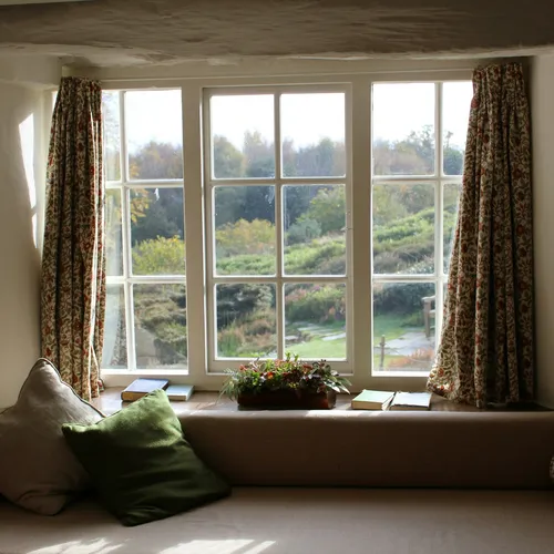Patterned curtains drawn open on a window above a cushioned window seat