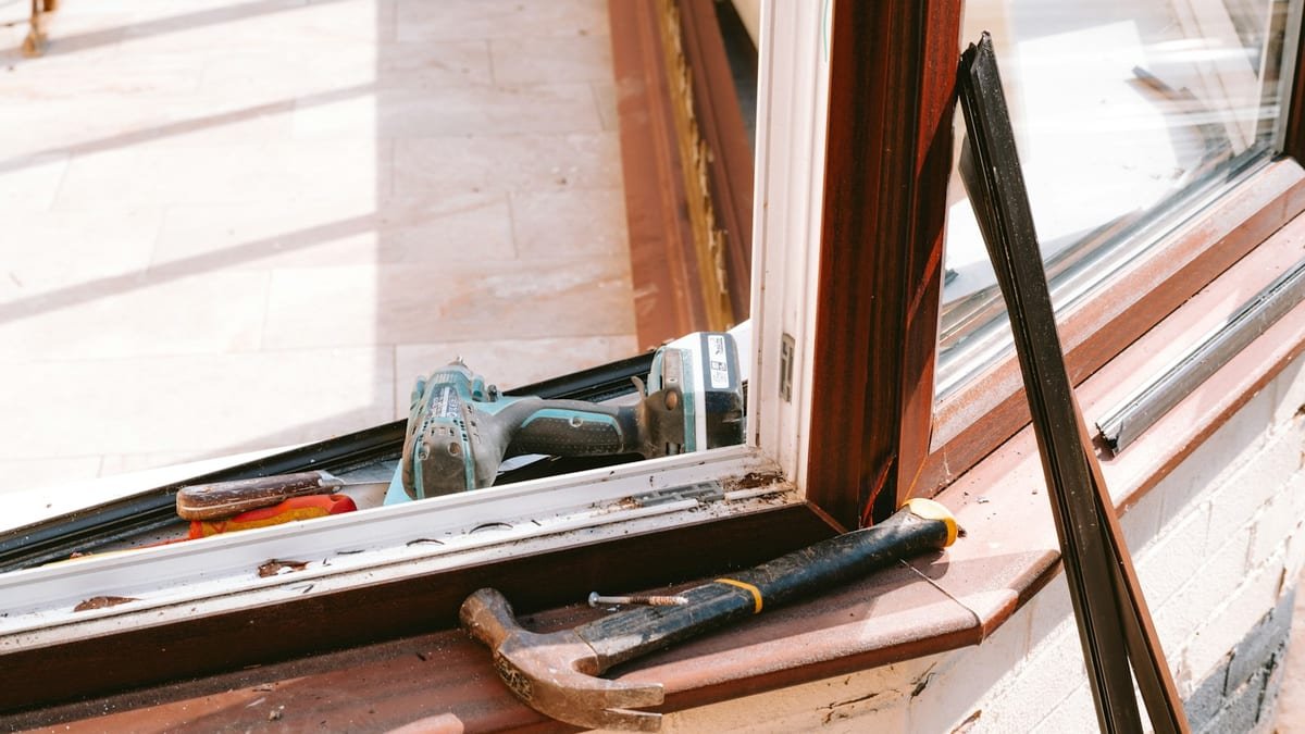 Hammer and cordless drill resting on a window sill during frame repair