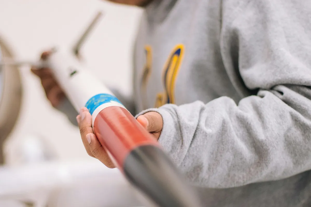 Hands holding a caulking gun loaded with a tube of sealant
