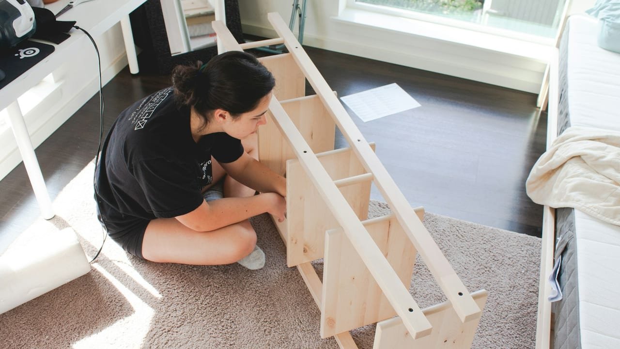 Woman assembling a wooden shelving unit on a living room floor