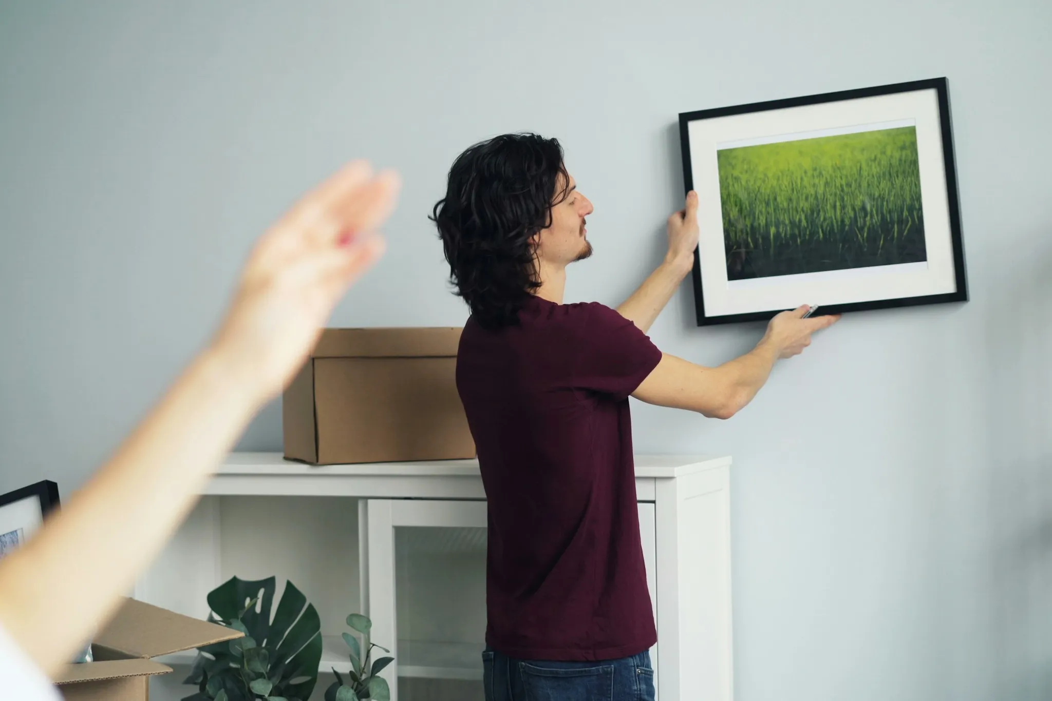 Man hanging a framed photo on a living room wall
