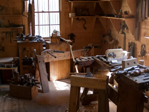 Woodworking shop with sturdy workbenches and hand tools hung on the walls