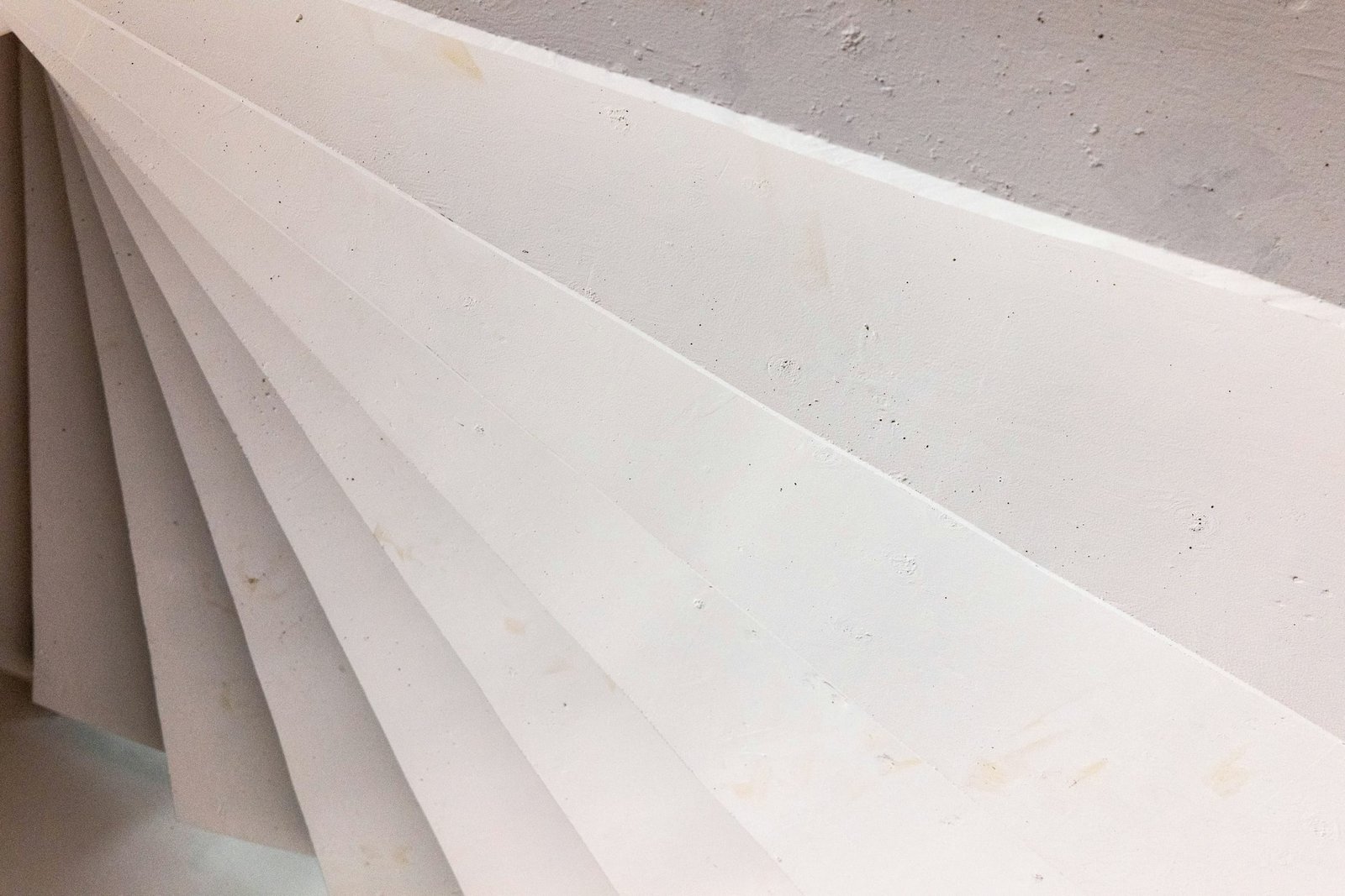 White wallboard panels leaning in a fanned stack against a wall